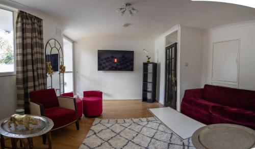 a living room with a red couch and red chairs at Regent's Park Sleeps 8 Pet Friendly & Garden in London