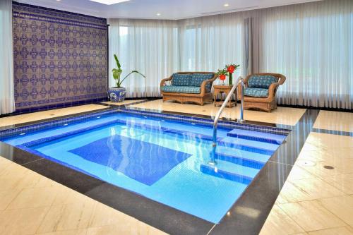 a swimming pool in a hotel room with two chairs at Meliá Caracas in Caracas