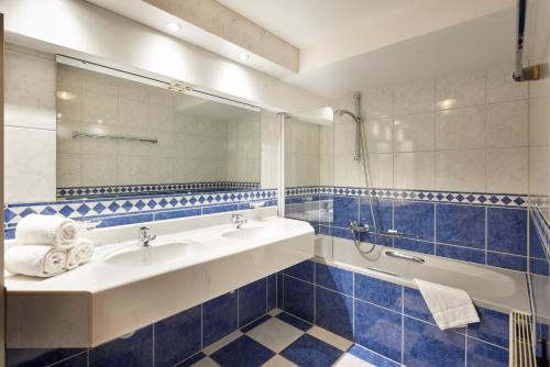a bathroom with a sink and a tub and a mirror at Alt Montafon Hotel Appartements by Pferd auf Wolke in Gaschurn