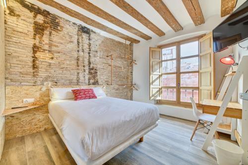 1 dormitorio con cama y pared de ladrillo en Casa Bidaiari by Clabao en Pamplona