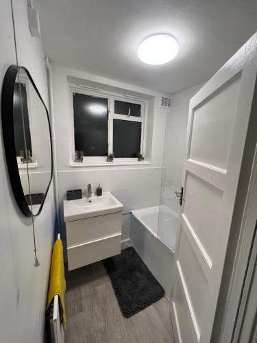 y baño blanco con lavabo y bañera. en a two bedroom cosy hideaway based in greenwich, en Londres