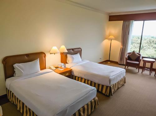 Cette chambre comprend 2 lits et une fenêtre. dans l'établissement โรงแรม ซี.เอส. ปัตตานี, à Ban Ru Sa Mi Lae