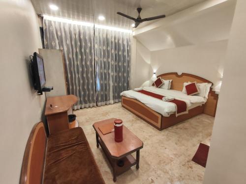 a bedroom with a bed and a tv and a table at Hotel Always Welcome in Mount Ābu