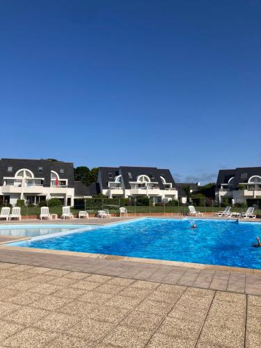 a swimming pool with chairs and buildings in the background at Au Ti Menhir * 2 à 4 vacanciers * Piscine * WIFI in Carnac