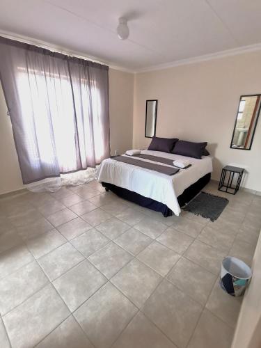 a bedroom with a bed and a large window at MV self-catering - Units in Bloemfontein