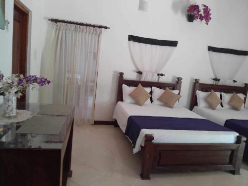 a bedroom with two beds and a table and flowers at Hemamala Bungalow in Anuradhapura