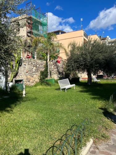 a park bench sitting in the grass near a building at SummerHouse in Mazzeo