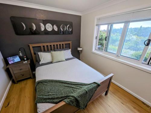 Un dormitorio con una cama y una ventana con relojes en la pared en Lunar Escape, en Glenbrook