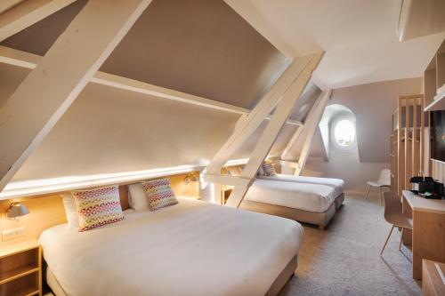 a bedroom with two beds and a desk and a window at Campanile Caen Centre Gare in Caen