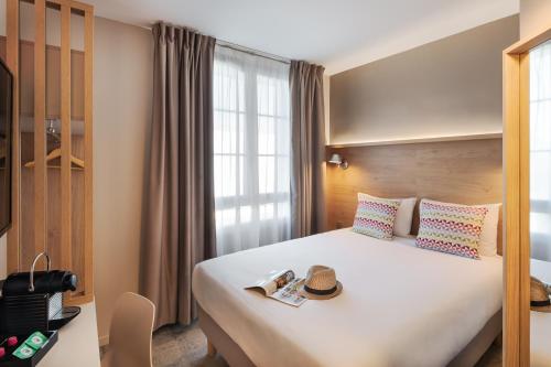 a hotel room with a bed with a hat on it at Campanile Caen Centre Gare in Caen