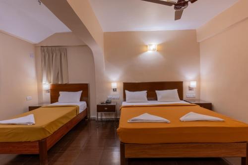 two beds in a room with yellow sheets at Sunshine Resort Calangute Goa in Calangute