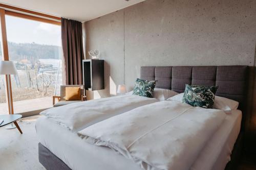 un grande letto bianco in una camera da letto con una grande finestra di *Relax Apartment Hochgraßnitzberg* in den südsteirischen Weinbergen a Spielfeld