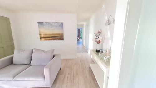 a white living room with a couch and a painting at Capelsound Beach house in Capel Sound