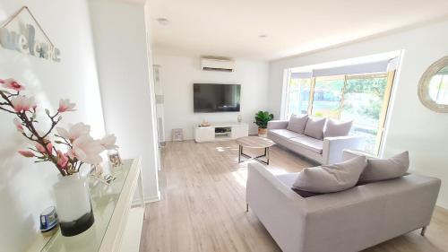 a white living room with a couch and a tv at Capelsound Beach house in Capel Sound
