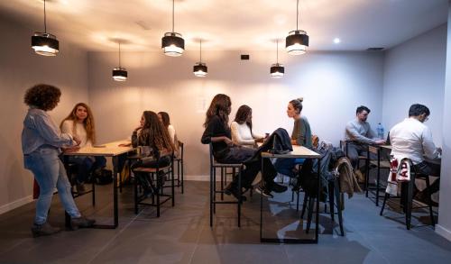 un gruppo di persone sedute ai tavoli in una stanza di Madriz Hostel a Madrid