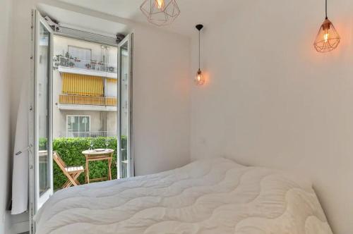 a white bedroom with a bed and a balcony at Superbe f1 au cœur du carré d’or terrasse/clim in Nice