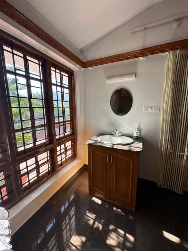 a bathroom with a sink and large windows at Nivi Homestay Ooty By Lexstays in Ooty