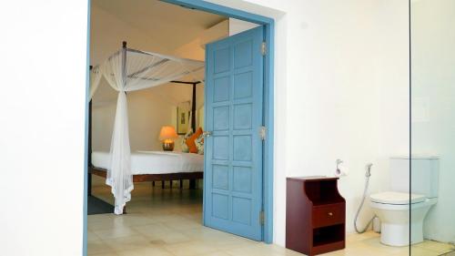 a bathroom with a blue door leading to a bed at Villa Apsara by Avant Garde in Aluthgama