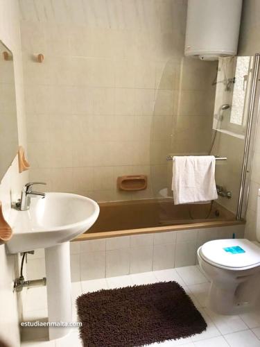 a bathroom with a sink and a toilet and a tub at EEM Only Girls Student Residence in Is-Swieqi