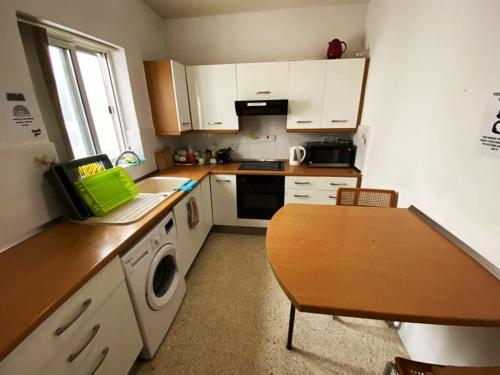 a kitchen with white cabinets and a wooden table at EEM Only Girls Student Residence in Is-Swieqi