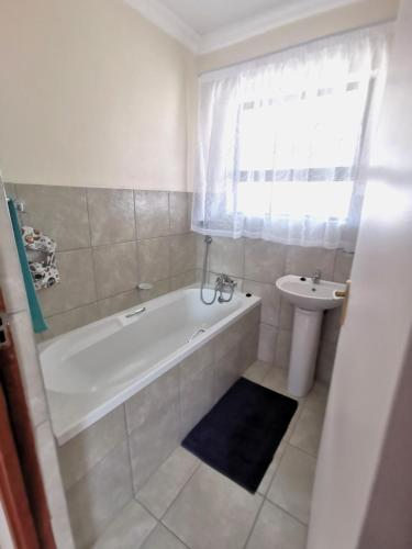 a white bathroom with a tub and a sink at MV self-catering - Rooms in Bloemfontein