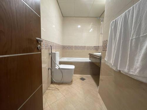 La salle de bains est pourvue de toilettes et d'une baignoire. dans l'établissement Get Premium Furnished 1 BR Apt, à Abu Dhabi