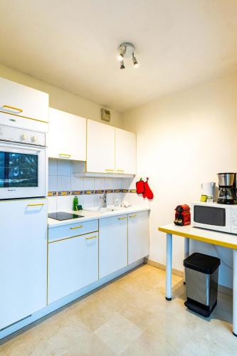 une cuisine avec des armoires blanches et une table dans l'établissement Le Gouverneur, 100m du lac avec parking, à Annecy