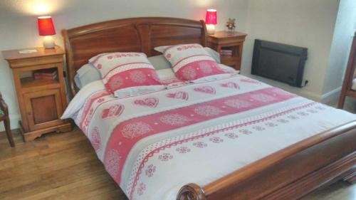 Cama grande con mantas y almohadas rojas y blancas en A la Grenouille du Jura, en Bellignat