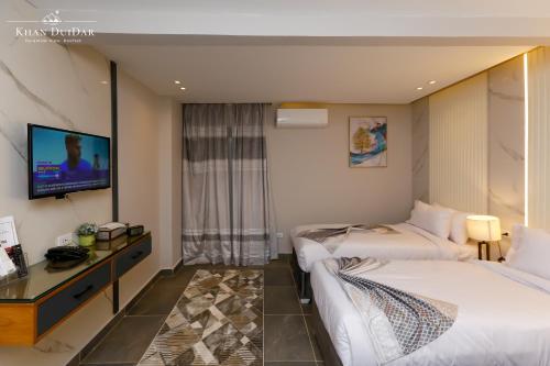 a hotel room with two beds and a flat screen tv at Khan Duidar Inn - Pyramids View Rooftop in Cairo