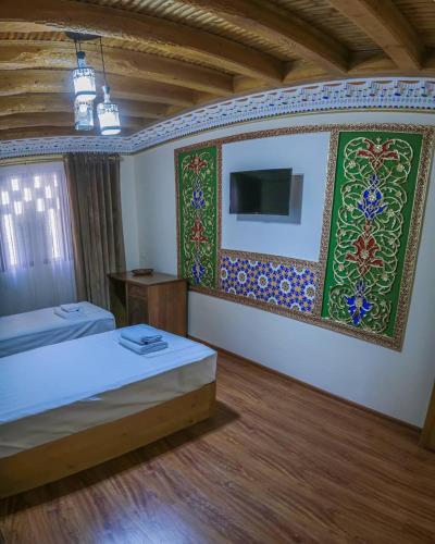 a bedroom with two beds and a tv on the wall at Antique hotel Imran in Bukhara