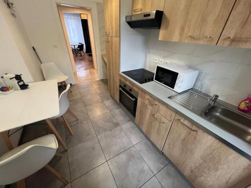 une petite cuisine avec un évier et un micro-ondes dans l'établissement Esprit Colmar - 2 chambres de charme, à Mulhouse