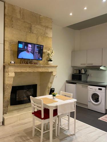 une cuisine avec une table et une télévision au-dessus d'une cheminée dans l'établissement Appart Cocoon / Rue Porte Dijeaux, à Bordeaux