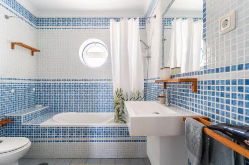 bagno piastrellato blu con vasca e lavandino di Aloha Apartment Arrifana a Praia da Arrifana