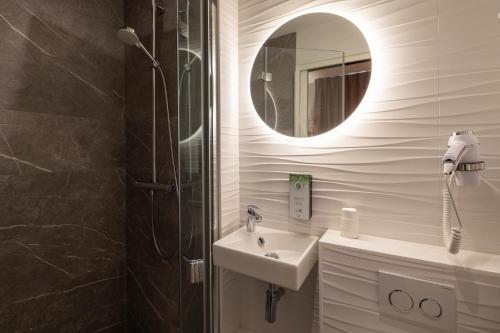 a bathroom with a shower and a sink and a mirror at Campanile Caen Centre Gare in Caen