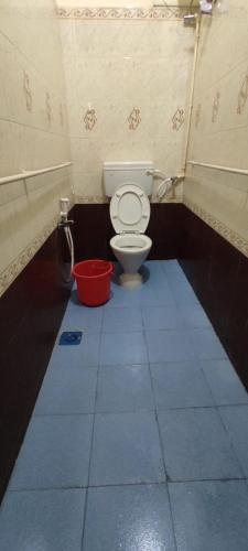 a bathroom with a toilet and a red bucket at Greenapple Inn in Chennai