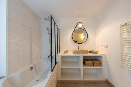 ein Badezimmer mit einer Badewanne, einem Waschbecken und einem Spiegel in der Unterkunft Les Cordeliers: 2 pers, cosy & cœur vieille ville in Annecy