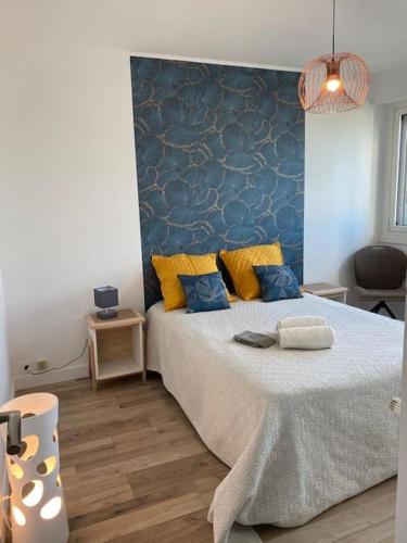 une chambre avec un lit avec des oreillers bleus et jaunes dans l'établissement Appartement spacieux (78m2)- vue imprenable, à Vannes