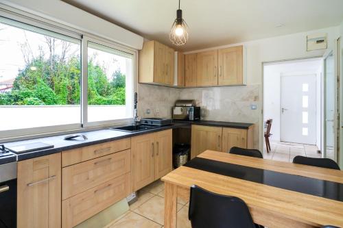 une cuisine avec des armoires en bois, une table et une fenêtre dans l'établissement Maison 3 chambres jardin 2km plage, à Boucau