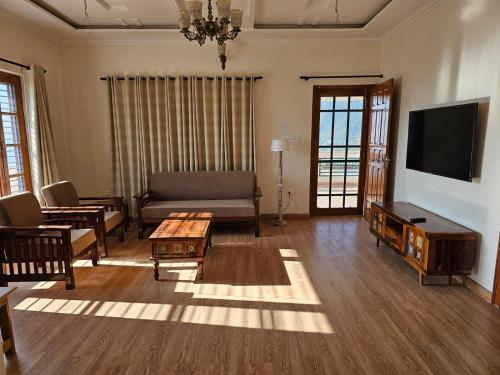 a living room with a couch and a tv at Laspa Cottage, Bhimtal in Bhīm Tāl