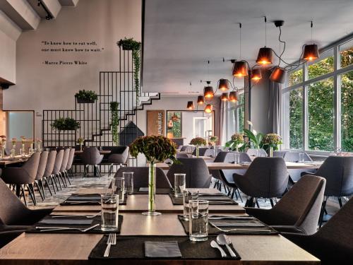 a dining room with tables and chairs and windows at Hotel Edison Poznań Lotnisko Ławica in Baranowo