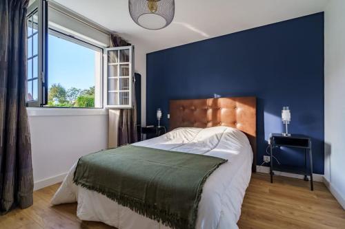 - une chambre avec un grand lit et un mur bleu dans l'établissement Appartement cosy pour 4 pers, en rez de jardin, à Cambo-les-Bains