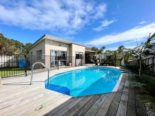 a swimming pool on a wooden deck next to a house at Surf Stay Ahipara - 200m to the beach 2m to the pool in Ahipara