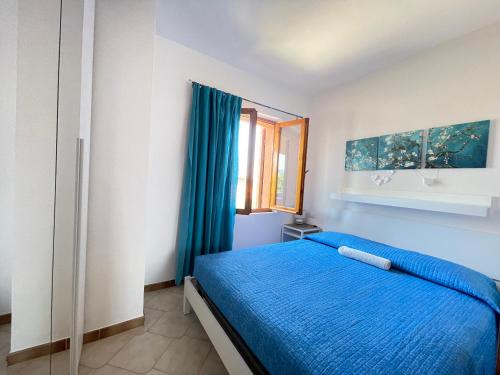 a bedroom with a blue bed and a window at Sunset House La Cinta ST5 - PuntoCasaBudoni in San Teodoro