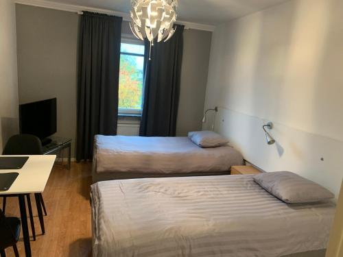 a room with two beds and a table and a chandelier at Vandrarhem Köping in Köping