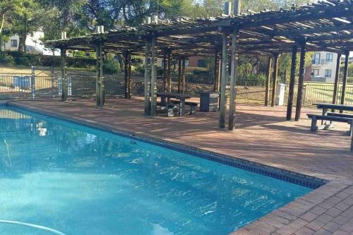 a swimming pool with a pavilion and a picnic table at Lustrous Loft Living in Penthouse in Roodepoort
