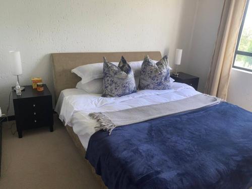 a bedroom with a bed with blue and white sheets and pillows at Lustrous Loft Living in Penthouse in Roodepoort