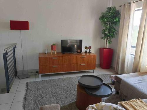 a living room with a tv on a wooden dresser at Lustrous Loft Living in Penthouse in Roodepoort