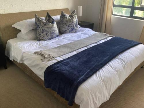 a large bed with blue and white sheets and pillows at Lustrous Loft Living in Penthouse in Roodepoort