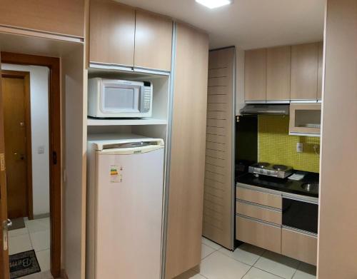 a small kitchen with a refrigerator and a microwave at Flat Asa Sul Condomínio Golden Place by CentoeDez in Brasilia