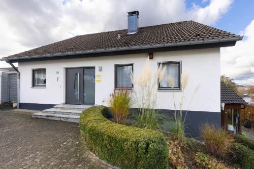 a white house with a hedge in front of it at Ferienwohnungen Lilie Und Dahlie in Münsingen